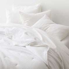 an unmade bed with white sheets and pillows