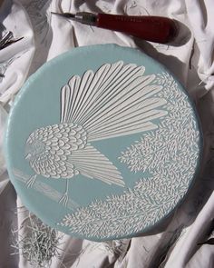 a blue and white plate with a bird on it's side next to scissors