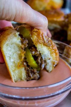 a hand is picking up a piece of bread that has been stuffed with meat and peppers