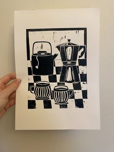 a hand holding up a piece of paper with an image of coffee pot and kettles on it