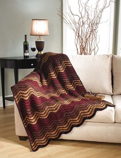 a couch with a blanket on top of it in a living room next to a table