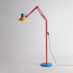 a red and yellow lamp sitting on top of a blue table next to a white wall