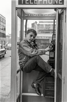 a man sitting on top of a telephone booth