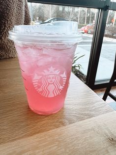 a pink drink sitting on top of a wooden table