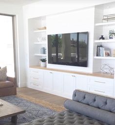 a living room filled with furniture and a flat screen tv mounted on a wall above a fireplace