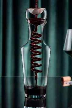 a wine glass filled with red wine being poured into the bottom and pouring it in