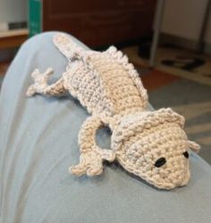 a crocheted gecko laying on the back of a couch