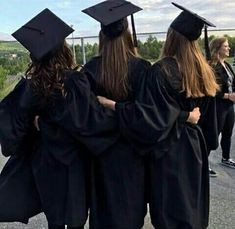 four graduates in black caps and gowns are standing on the side of the road