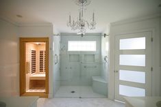 a white bathroom with a chandelier hanging from the ceiling and a walk in shower