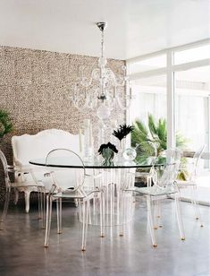 a glass dining table surrounded by white chairs