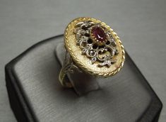 "Vintage Circa 1950 Constructed of 18KT Yellow Gold with Sterling Silver accents (18KT Ring - Sterling Silver Filigree at top + Sterling Silver Side Fleur de Lis designs) Containing 1 Genuine Earth-Mined Oval cut Natural Deep Red Ruby weighing approximately 0.60 carats Ruby measuring approximately 5mm x 3.6mm Note: Ruby does contain natural internal inclusions, as well as some coming up to the surface (a.k.a. striation).. Not any kind of damage to the stone, simply a characteristic of earth-mine Vintage Ruby Ring With Diamond Cut, Oval Filigree Ring With 17 Jewels For Anniversary, Estate Oval Rings For Formal Occasions, Estate Style Oval Rings For Formal Occasions, Formal Oval Estate Rings, Vintage Oval Signet Ring With Diamond Cut, Vintage Oval Diamond Cut Signet Ring, Luxury Antique Oval Cabochon Ruby Ring, Luxury Yellow Gold Ruby Ring Oval Cabochon