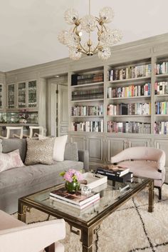 a living room filled with furniture and a chandelier above a glass coffee table