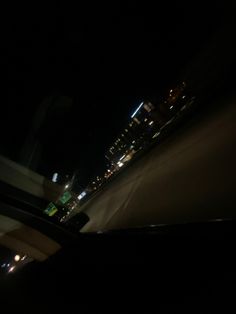 the view from inside a car at night time with city lights in the back ground