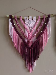 there is a pink and purple wall hanging with beads on the end of each piece