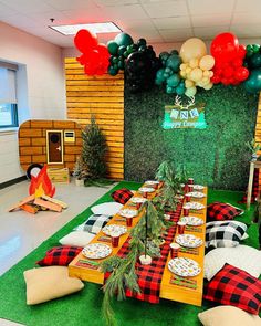 a table set up for a party with red, white and green balloons on the wall