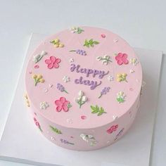 a pink birthday cake decorated with flowers and the words happy day on it's side