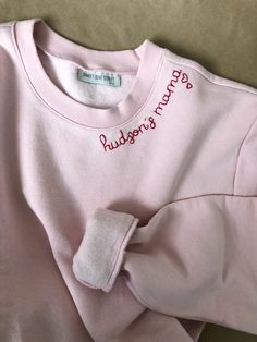 Mamas favorite names hand stitched in red thread on a cozy faded pink sweatshirt. Add a special touch with hearts on the sleeve or collar - one heart for each little one :) Sweatshirts are Unisex sizing and run true to size. I suggest sizing up for a more oversized fit. 70/30 cotton/polyester 3-End fleece, ring spun cotton *Please note that all sweatshirts for this listing are for faded pink long-sleeved crewneck with set-in rib neckband, cuffs & hem band. If you are looking for a specific c Pink Sweatshirt With Embroidered Logo For Spring, Pink Crew Neck Sweatshirt With Ribbed Cuffs, Pink Sweatshirt With Ribbed Cuffs And Crew Neck, Pink Long Sleeve Sweatshirt With Embroidered Logo, Cute Pink Sweatshirt With Ribbed Cuffs, Pink Crew Neck Sweater With Ribbed Cuffs, Pink Crew Neck Sweater With Embroidered Logo, Pink Crew Neck Top With Embroidered Logo, Pink Relaxed Fit Crew Neck Sweater