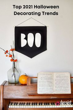 an open book sitting on top of a piano next to a vase filled with flowers