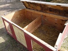 an open wooden box with straw inside on the ground