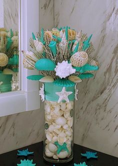 a vase filled with shells and starfish on top of a table