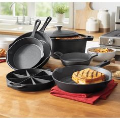 an assortment of cast iron pans and skillets on a wooden countertop in a kitchen