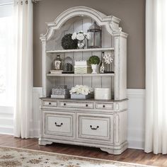 a white china cabinet with flowers on top