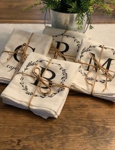 napkins tied up with twine on top of a wooden table next to a potted plant