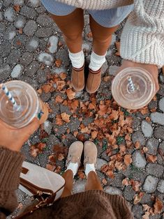 two people standing next to each other with their feet on the ground and one holding a plastic cup