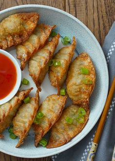 some fried food is on a plate with sauce and chopsticks next to it