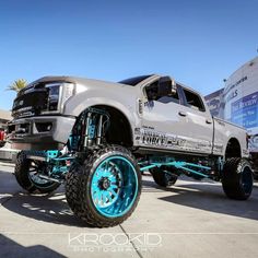 a silver truck with blue wheels parked in a parking lot