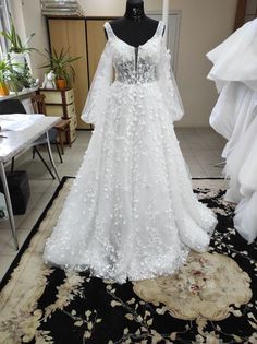 a white wedding dress on display in a room with black and white carpeted flooring