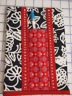 a red and black notebook cover with white flowers on it, sitting on a table