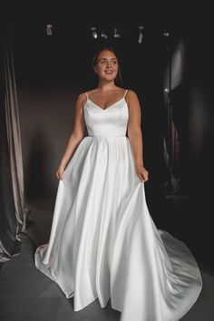 a woman in a white dress is posing for the camera