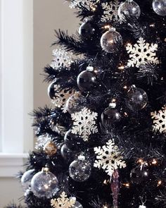 a black christmas tree with silver and white ornaments