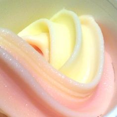 a white bowl filled with pink and yellow liquid next to an orange slice on top of it