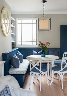 a white table and chairs in a room with blue walls, wood flooring and built - in shelving