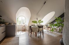 a dining room table and chairs in front of an arched window with potted plants