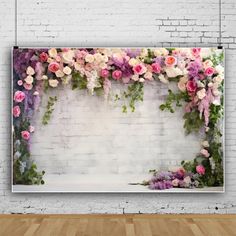 a white brick wall with pink and purple flowers hanging on it's side, next to a wooden floor