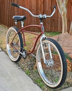 a bike parked on the side of a road next to a wooden fence and tree