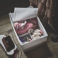 an open suitcase sitting on top of a wooden floor next to a necklace and other items