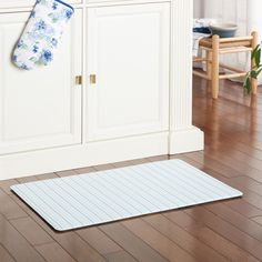 a kitchen area with white cabinets and wooden floors, including a rug on the floor