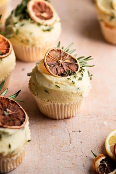 cupcakes with orange slices and herbs on top, surrounded by sliced lemons