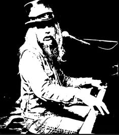 a black and white photo of a man with long hair playing the piano in front of a microphone