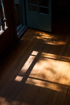 the sun shines through two windows onto a wood floor in front of a door