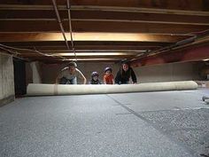 three people standing in an unfinished room with a mattress on the floor and one person holding a skateboard