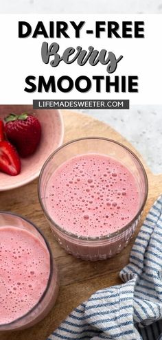 two glasses filled with strawberry smoothie on top of a wooden cutting board next to strawberries