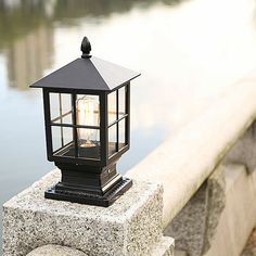 a lantern is sitting on a stone ledge by the water