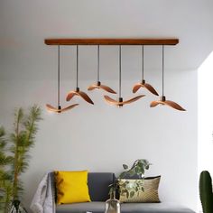 a living room filled with furniture and plants next to a wall mounted ceiling light fixture