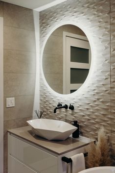 a bathroom with a round mirror above the sink and a bowl on the counter in front of it