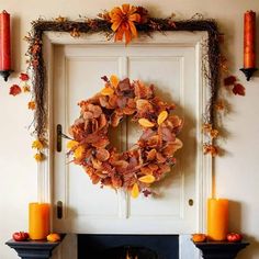 a wreath is hanging on the wall next to a fire place with candles and pumpkins